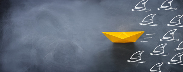 concept banner of avoiding crisis. paper boat escaping sharks idea