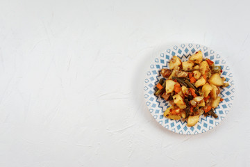 baked potato with vegetables and meat on the plate on the white background. Potatoes with carrot and bean. Copy space. 