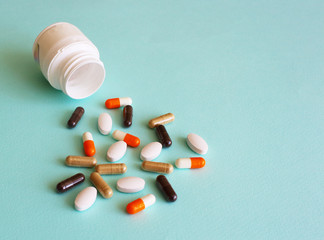 A handful of colored pills spilled out of the can on a blue background. Medical concept.