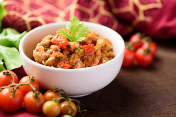 Northern Thai food (Nam Prik Ong), spicy chili minced pork with tomatoes in a bowl on wooden background, Thai chili paste