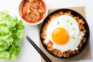 Kimchi fried rice with fried egg on top in a bowl and chopsticks ready to eating, Korean food, Top view