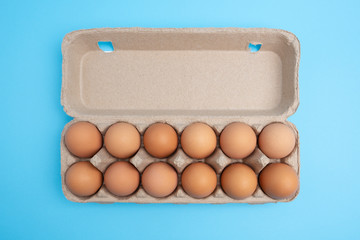 Dozen eggs in open carton on blue background. Top view with copy space - Powered by Adobe