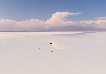 Couple in Salt Flats Uyuni Bolivia. Romantic tourists on beautiful mirror reflection on blue sky and cloud. DRONE Shot in Salar de Uyuni salt flat. Holiday, love, adventure vacation honeymoon travel