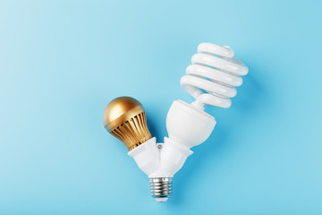Gold LED light bulb and energy-saving in a double base on a blue background.
