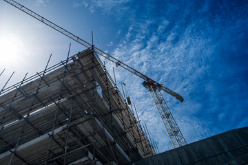 Building site with scaffolding and construction crane. Concrete building under construction