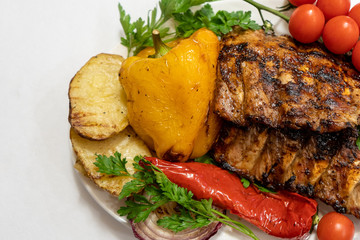 Grilled pork ribs with vegetables on the white plate