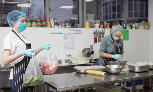 Kitchen workers cooking of fresh ingredients and wearing protective gloves