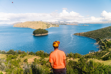 Fototapeta premium Tourist MAN on Island at Isla del Sol in Bolivia. Scenic panoramic view of island and sea horizon. Bolivian island paradise and hills. Walking trail, by boat. Local community, tourism. Titicaca lake