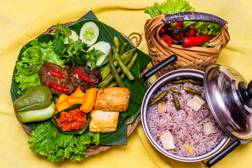 Indonesian traditional food nasi liwet with empal daging, tahu, sambal and lalapan served with rice and assorted vegetables
