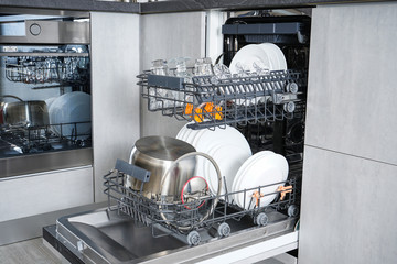 Dishwasher, open and loaded with dishes in the kitchen, after washing.