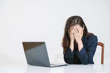 Stressed asian woman sitting at office desk with laptop 