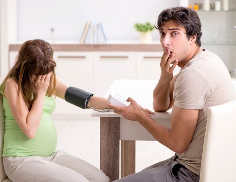 Husband checking pregnant wife's blood pressure