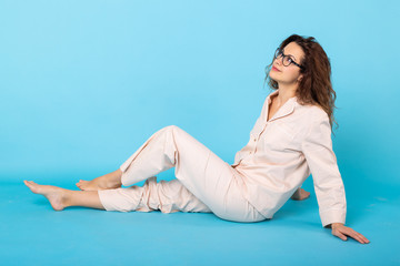 Smiling young girl in pajamas home wear posing while resting at home isolated on blue background studio portrait. Relax good mood lifestyle concept.