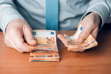 Bank teller count euro banknotes on a wooden desk