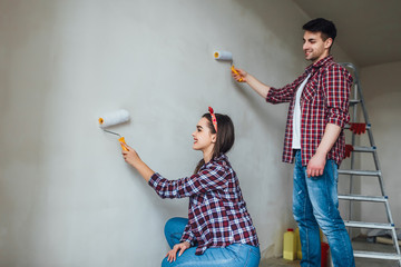 Repair, renovation and love couple concept - young family doing repair and painting walls together...