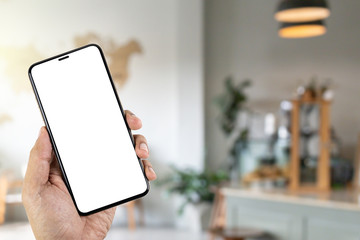 Mockup image of hand holding smartphone with blank white screen in the coffee shop.