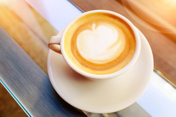 A cup of coffee or cappuccino in the white cup. On the milk foam art apple. View from above. Sunny day.