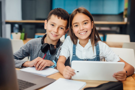 Two Happy Small Friends Writing Homework , Using Smart Digital Tablet At Modern Blue Classroom.