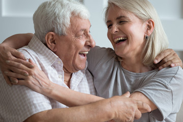 Overjoyed mature husband and wife relax on couch have fun laughing joking together, happy senior couple rest on sofa ta home, smile enjoy leisure family romantic weekend at home, elderly love concept