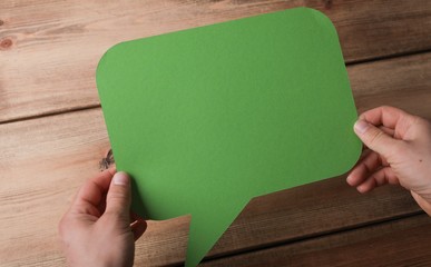 High angle closeup shot of a man holding a green message icon on a wooden background
