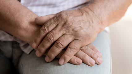 Close up of senior man sit hold hands feeling lonely or abandoned in retirement house, old male patient thinking pondering of life problems, miss good old days, elderly solitude, loneliness concept