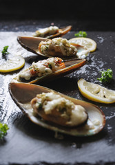 New Zealand Mussels baked with butter, garlic, parsley and cheese, on black stone plate