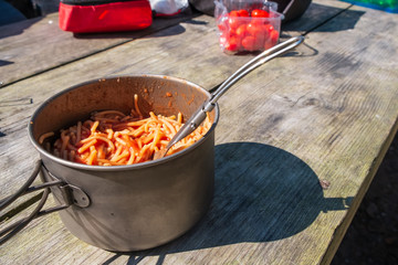 Cooked vermicelli with tomato paste during a picnic in a metal pot