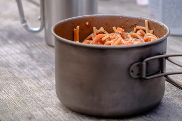 Cooked vermicelli with tomato paste during a picnic. Vermicelli is in a metal pot