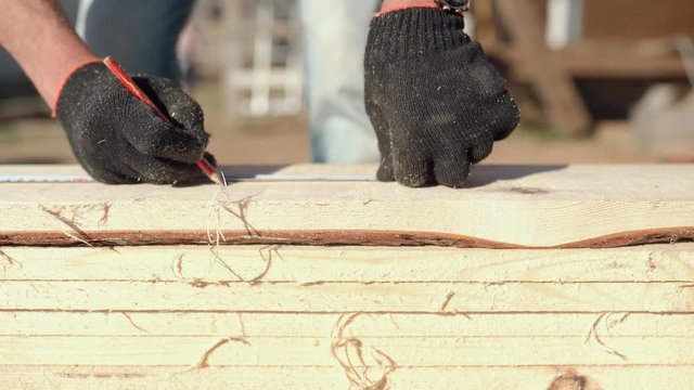 View from above. Carpenter with the pencil and the carpenter's square drawing the cutting line on a wooden board. Construction industry, do it yourself. Wooden work table.