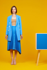 High fashion portrait of young elegant woman in blue jacket and skirt.
