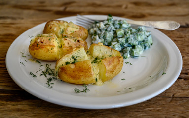 Baked potatoes with cheese and cocumber salad with sour cream, Selective focus.
