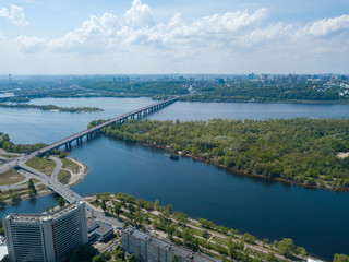 Fototapeta na wymiar View of the Dnieper River in Kiev. Green trees on the banks of the river. Sunny spring day. Aerial drone view.