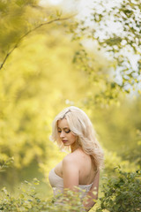 Fototapeta na wymiar Blonde girl in a dress enjoys spring nature