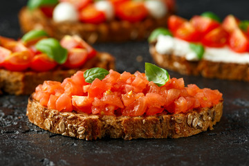 Bruschetta with sliced tomato, basil on rustic table