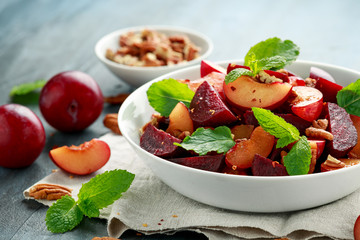 Vegan Plum, beet salad with pecan nuts, mint and herbs in white bowl. healthy summer food.