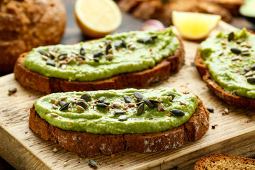 Healthy Homemade Avocado creamy Toast with nuts mix on wooden board