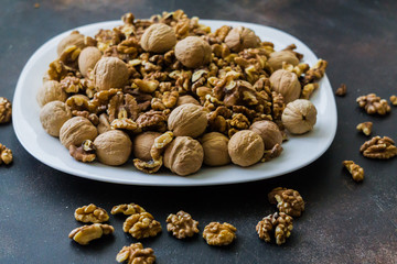 Walnuts peeled and in shells on a table in a plate.
