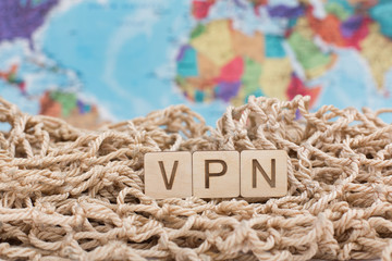 Wooden sign VPN made of wooden alphabet letters, working concept. Fishnet and world map background