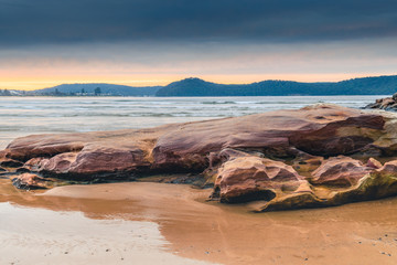 Stratocumulus Cloud Covered Sunrise Seascape and large rock on beach
