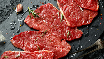 Raw fresh sizzling beef steak with herbs on stone board