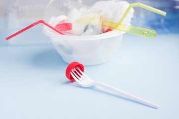 Fork with bottle cap against pile of single use plastic garbage. Concept of environmental pollution with plastic.