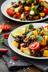 Avocado, mango salad with black bean on white plate