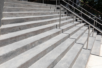 Tall wide concrete staircase on a building exterior, silver stainless railings, horizontal aspect