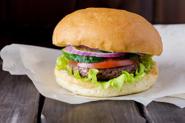 Big tasty burger at craft paper and dark wood background