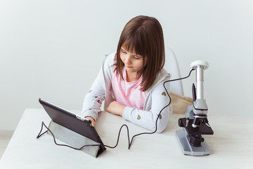 Child girl in science class using digital microscope. Technologies, children and learning concept.