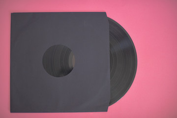 Vinyl record in sleeve isolated against pink background