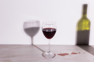Bottle with wine and glass, red puddle of wine on the table. Cleaning after party concept.