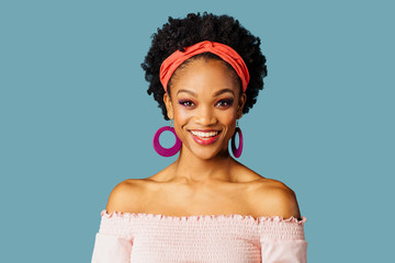 Portrait of a young woman with loop earrings smiling and looking at camera isolated on blue color background