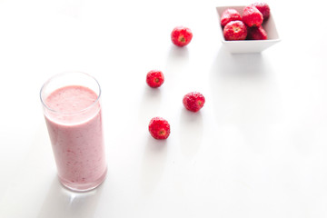 Minimal view of strawberry smoothie and strawberries over flat white background with copy space