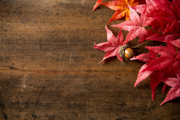 Naklejka na ściany i meble Wooden background with artificial autumn maple leaves.